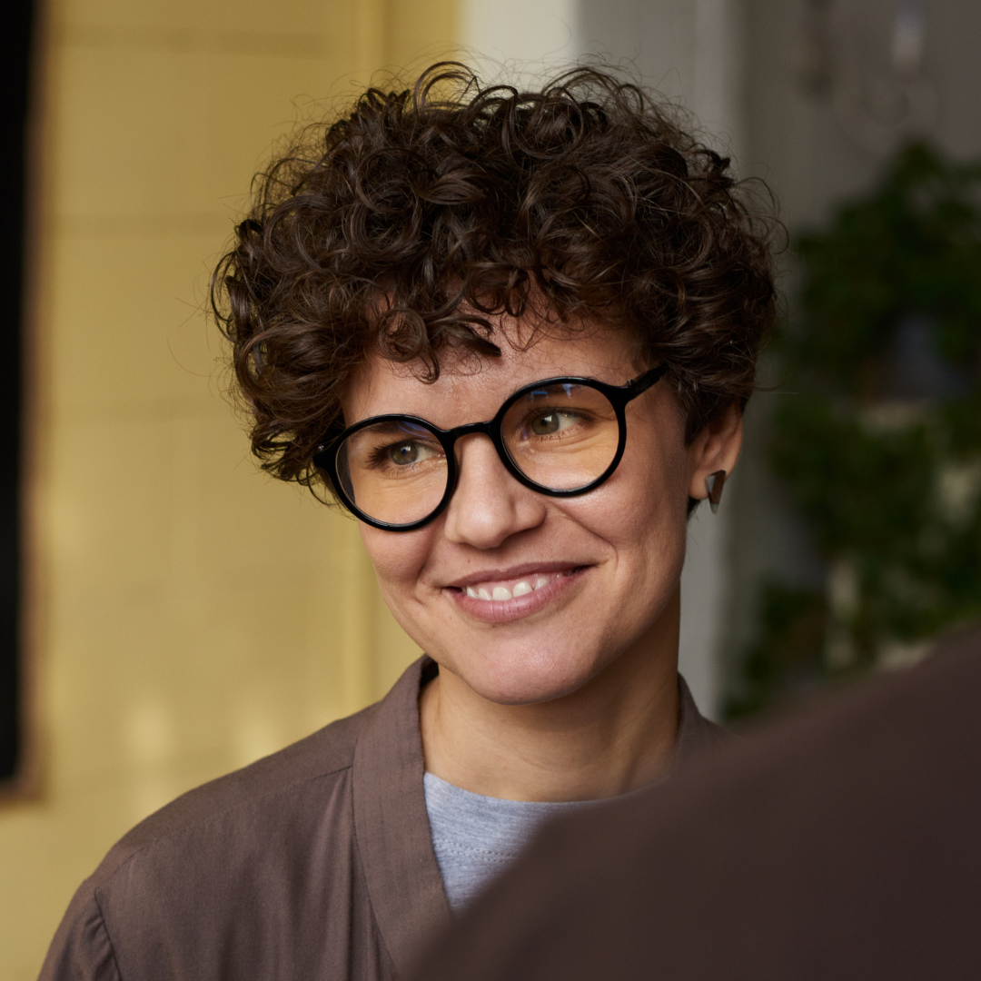 A black man with glasses in a light background